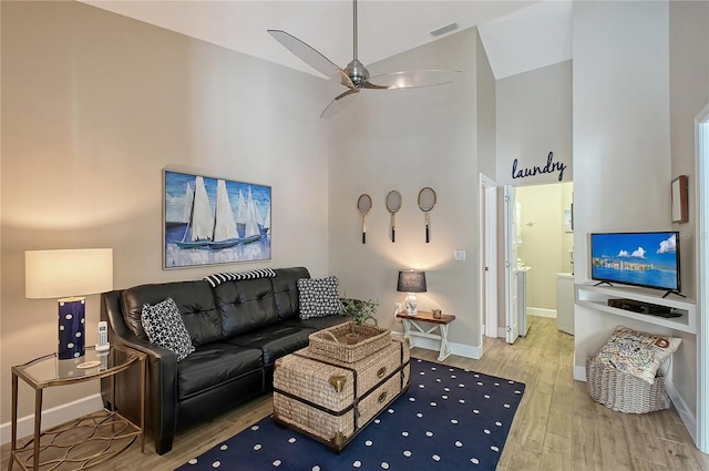 living area with visible vents, baseboards, ceiling fan, wood finished floors, and high vaulted ceiling