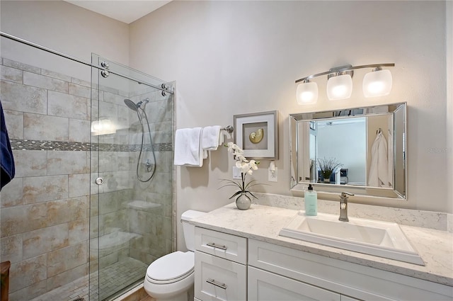 bathroom with vanity, a shower stall, and toilet