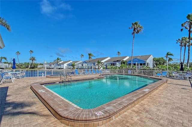 community pool featuring a residential view, a patio, and fence