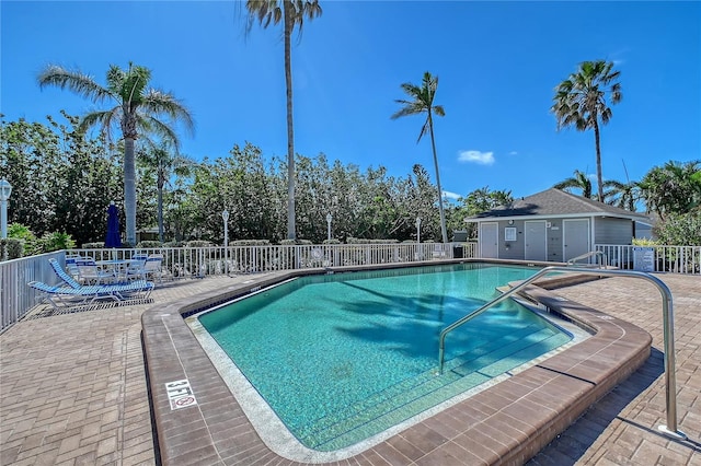 community pool with a patio area and fence