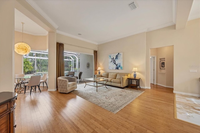 living room featuring visible vents, light wood-style flooring, baseboards, and ornamental molding