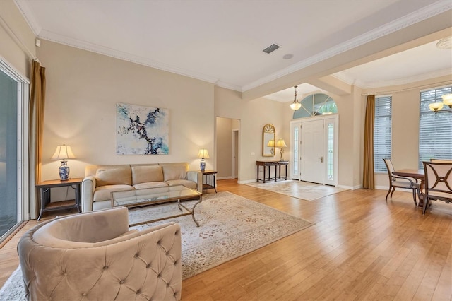 living room with baseboards, visible vents, light wood-style flooring, arched walkways, and ornamental molding