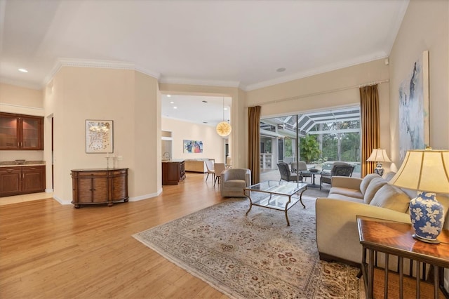 living area with baseboards, recessed lighting, a sunroom, ornamental molding, and light wood-style floors