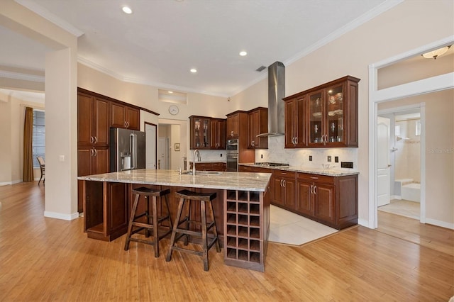 kitchen featuring crown molding, wall chimney range hood, appliances with stainless steel finishes, and a sink