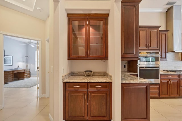 kitchen with visible vents, tasteful backsplash, stainless steel appliances, wall chimney exhaust hood, and light stone countertops