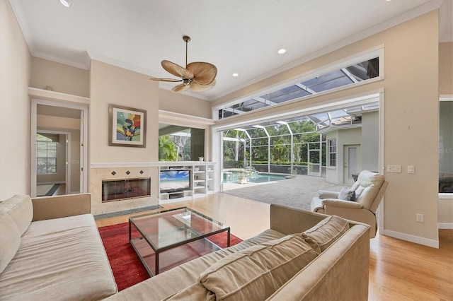 living area featuring ornamental molding, wood finished floors, a ceiling fan, and a sunroom