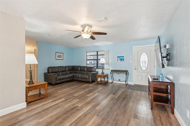 living room with ceiling fan, plenty of natural light, dark wood-type flooring, and a textured ceiling