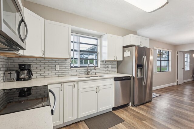 kitchen featuring light hardwood / wood-style flooring, sink, appliances with stainless steel finishes, white cabinets, and decorative backsplash