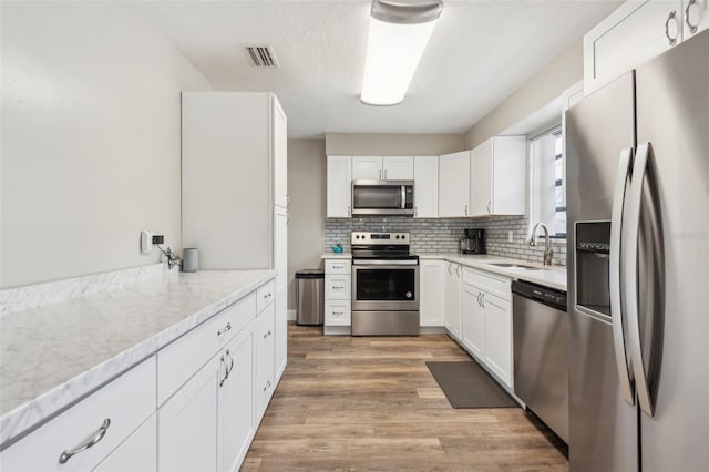 kitchen with white cabinetry, appliances with stainless steel finishes, sink, and light hardwood / wood-style floors