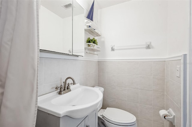 bathroom featuring tile walls, vanity, and toilet