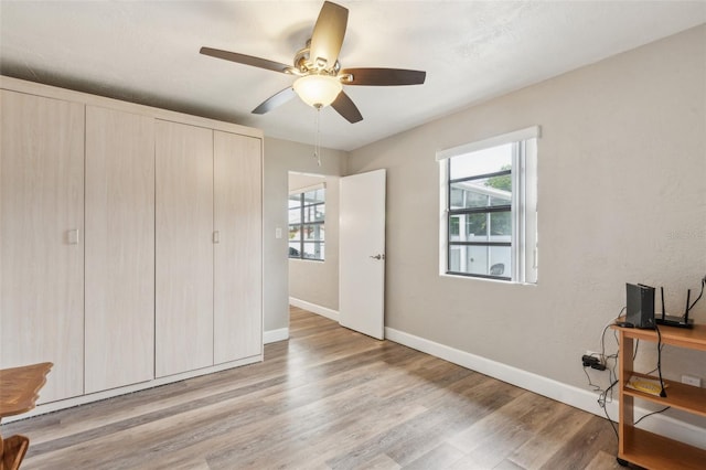 bedroom with multiple windows, ceiling fan, and light hardwood / wood-style floors