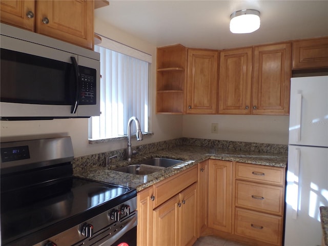 kitchen with stainless steel appliances, dark stone counters, and sink