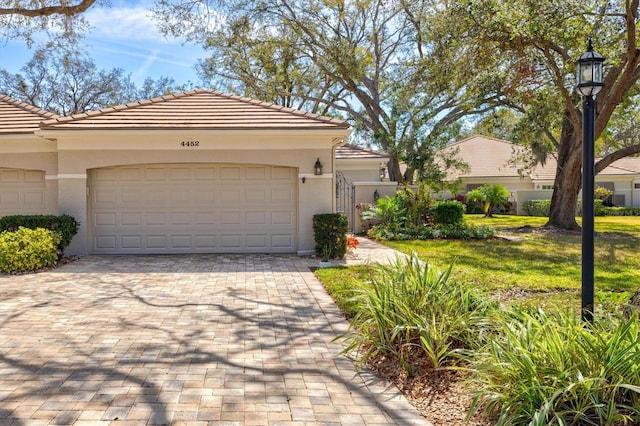 mediterranean / spanish home featuring a front lawn, decorative driveway, a tile roof, and stucco siding