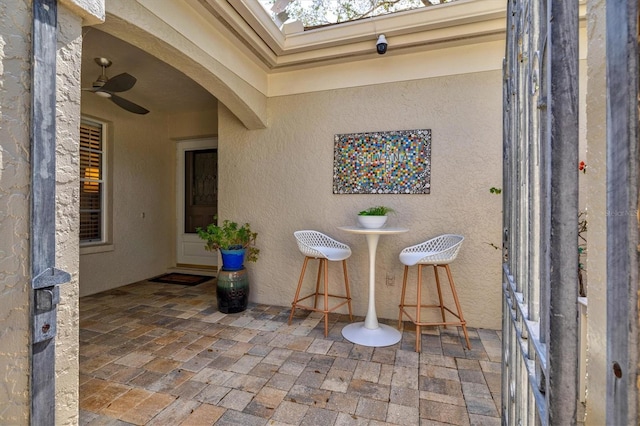 view of exterior entry featuring a ceiling fan, a patio area, and stucco siding