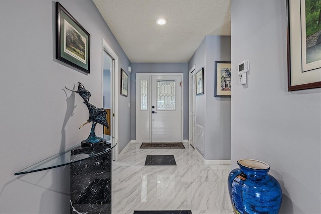 entryway with marble finish floor, visible vents, a textured ceiling, and baseboards