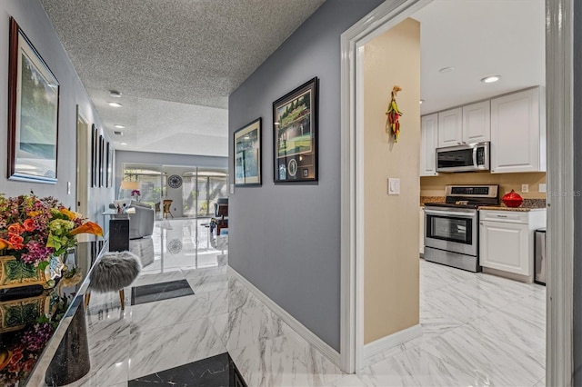 corridor with a textured ceiling, marble finish floor, recessed lighting, and baseboards