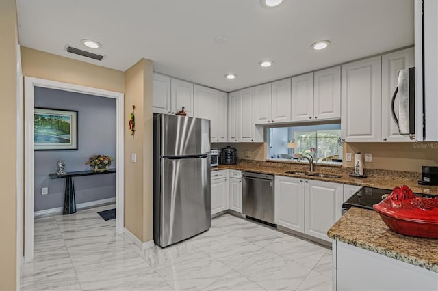 kitchen featuring stone countertops, stainless steel appliances, a sink, visible vents, and white cabinets