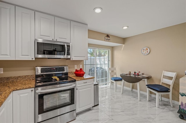 kitchen with white cabinets, stainless steel appliances, and dark stone countertops