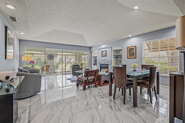 dining room with visible vents, marble finish floor, a lit fireplace, a textured ceiling, and recessed lighting