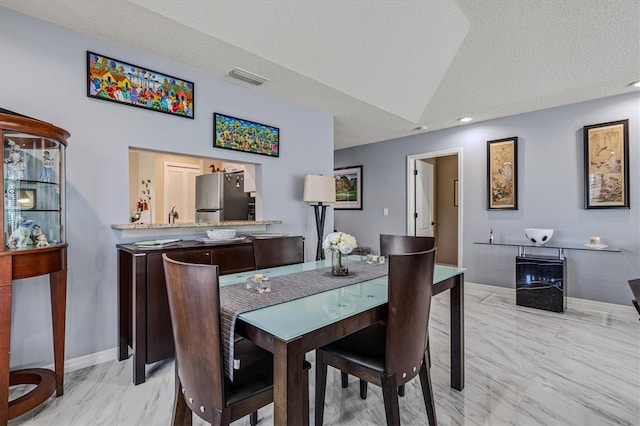 dining area featuring marble finish floor, visible vents, vaulted ceiling, a textured ceiling, and baseboards