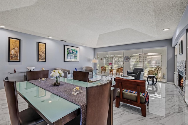 dining area featuring marble finish floor, a lit fireplace, a textured ceiling, and recessed lighting