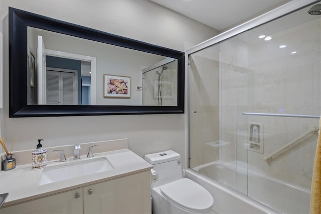 bathroom with combined bath / shower with glass door, vanity, and toilet