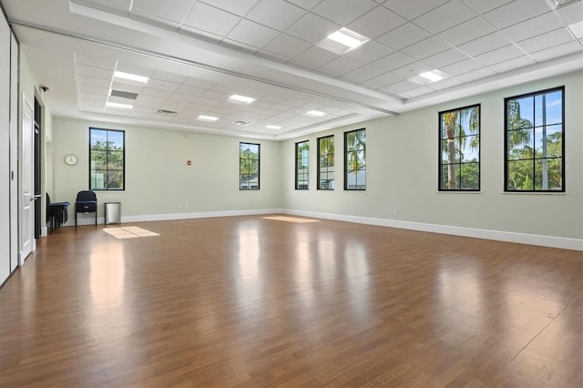 spare room featuring a drop ceiling, wood finished floors, and baseboards