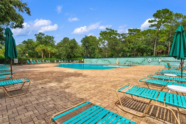 pool with a patio area and fence