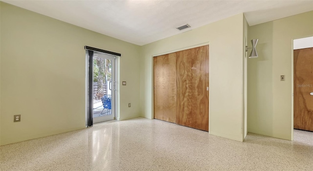 unfurnished room with light speckled floor, visible vents, and baseboards