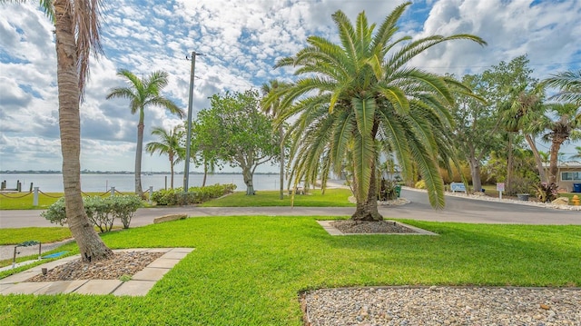 surrounding community with a water view and a yard