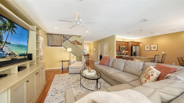 living room with ceiling fan, light hardwood / wood-style flooring, and sink