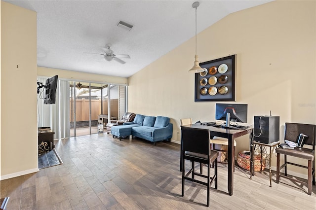 office space with vaulted ceiling, visible vents, wood finished floors, and a ceiling fan