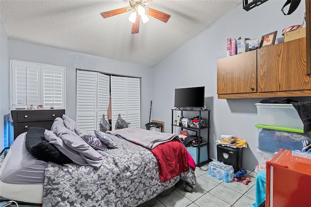 bedroom featuring light tile patterned floors, ceiling fan, vaulted ceiling, a textured ceiling, and a closet