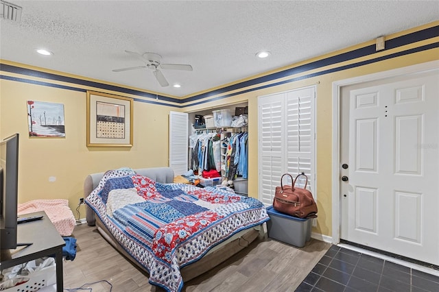 bedroom with visible vents, ceiling fan, wood finished floors, a textured ceiling, and a closet