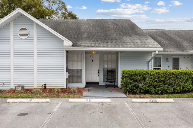 view of front of property with a shingled roof and uncovered parking