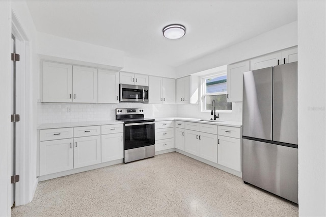 kitchen with appliances with stainless steel finishes, light countertops, a sink, and white cabinetry