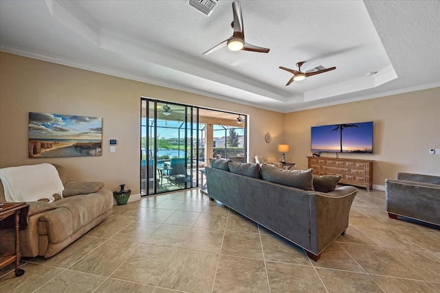 living room with a raised ceiling, a textured ceiling, ceiling fan, and ornamental molding