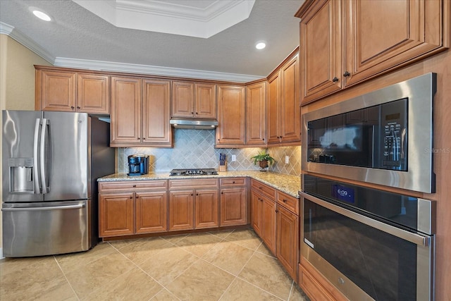 kitchen featuring crown molding, backsplash, light stone countertops, and stainless steel appliances