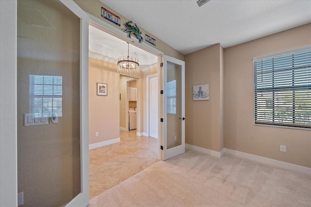 carpeted spare room featuring washer / clothes dryer and a chandelier