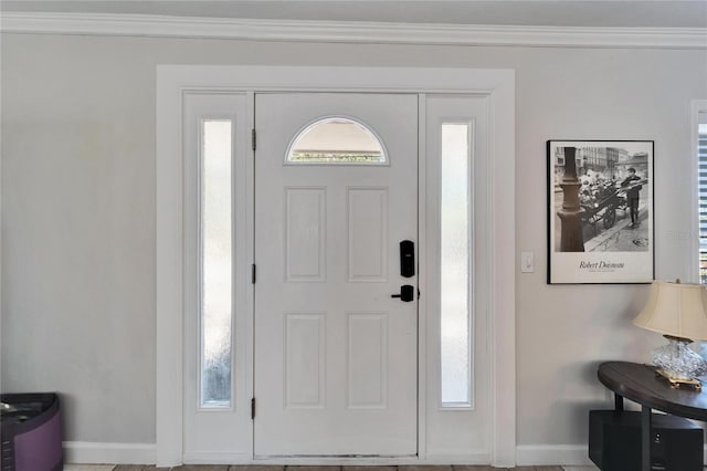 foyer entrance featuring baseboards, ornamental molding, and a wealth of natural light