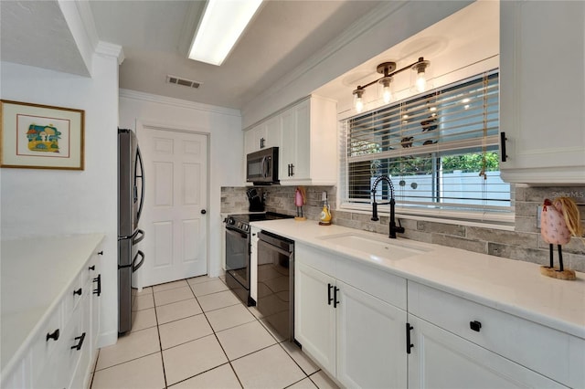 kitchen with white cabinets, ornamental molding, light countertops, black appliances, and a sink