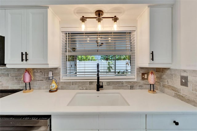 kitchen featuring dishwashing machine, a sink, light countertops, and white cabinets