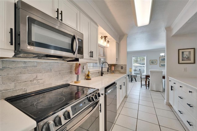 kitchen featuring stainless steel appliances, white cabinets, light countertops, and a sink