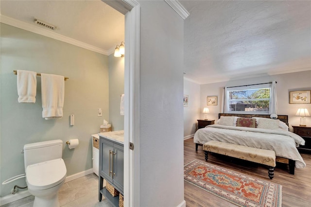 bedroom featuring a textured ceiling, visible vents, baseboards, ornamental molding, and light wood-type flooring