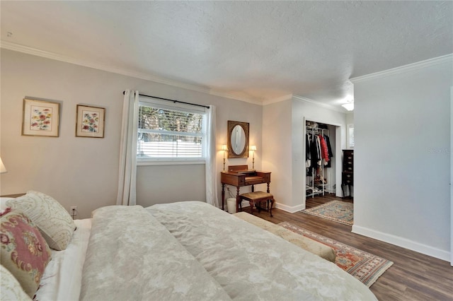 bedroom featuring baseboards, dark wood-style floors, ornamental molding, a textured ceiling, and a closet