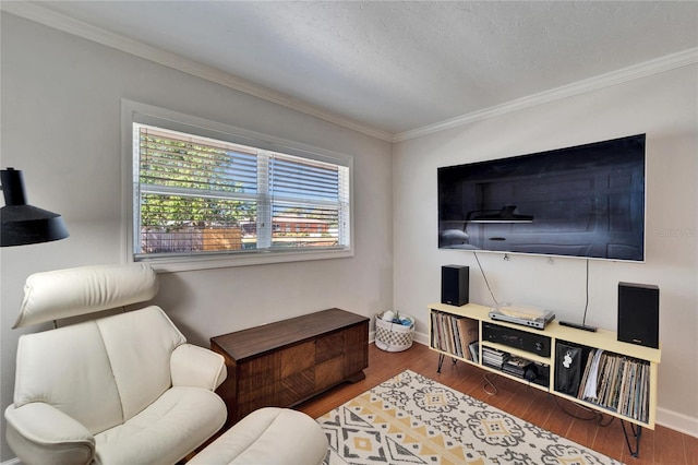 living room featuring crown molding, a textured ceiling, baseboards, and wood finished floors