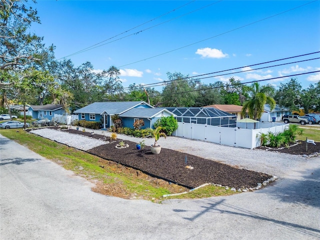 ranch-style house with driveway, glass enclosure, a fenced front yard, and a residential view