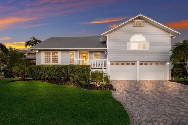 1528 43rd Avenue Dr W, Palmetto, FL 34221 - split level home featuring decorative driveway, a porch, a lawn, metal roof, and an attached garage