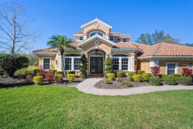 view of front of home featuring stucco siding, a tiled roof, a front lawn, and french doors