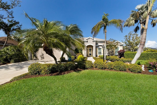 mediterranean / spanish house with an attached garage, a front lawn, concrete driveway, and stucco siding